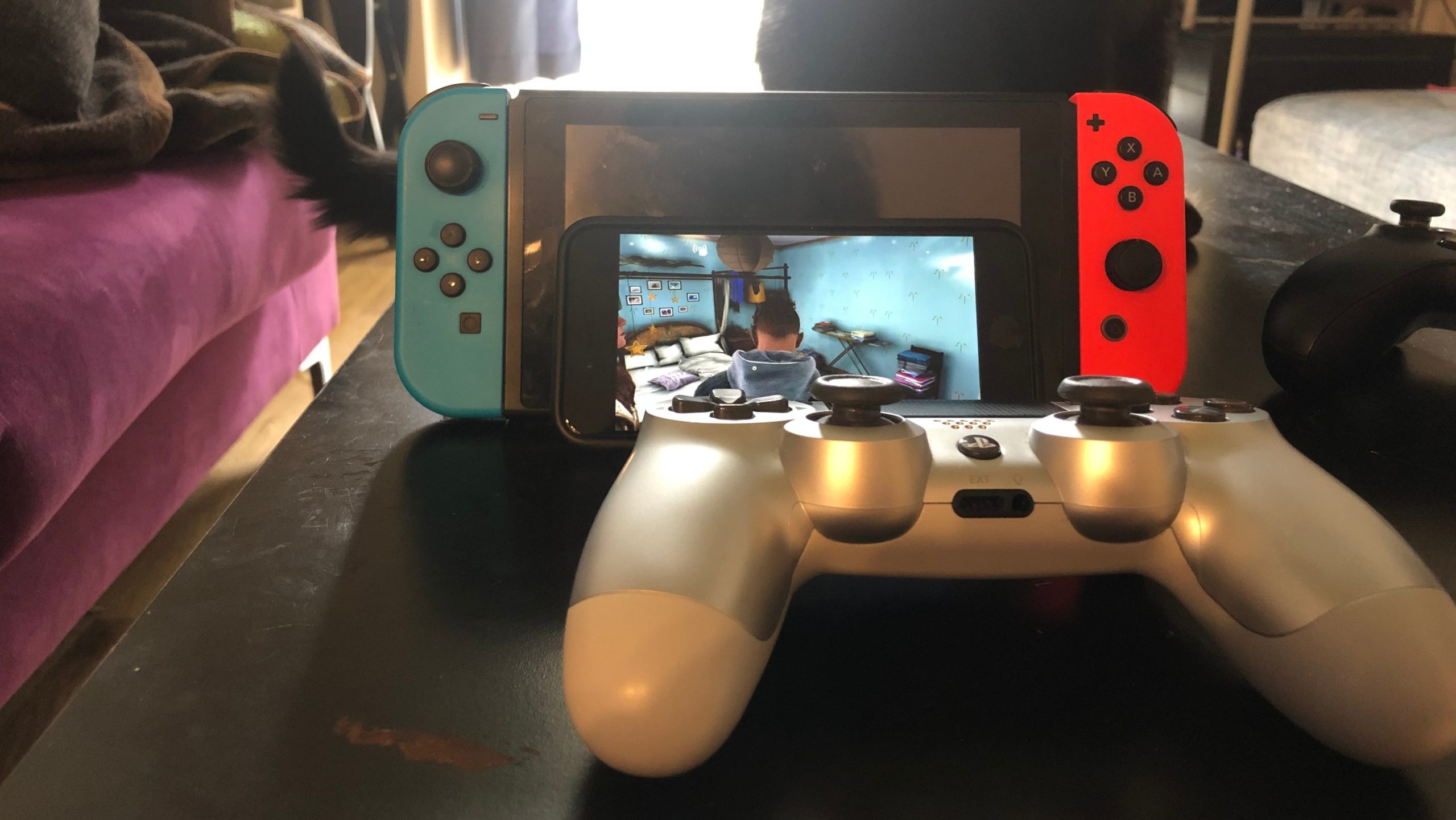 Yes, that's me using a PS4 controller to play Xbox games on an Apple phone leaning up against a Nintendo console. How's that for Corporate Synergy®? (Photo: Kotaku)