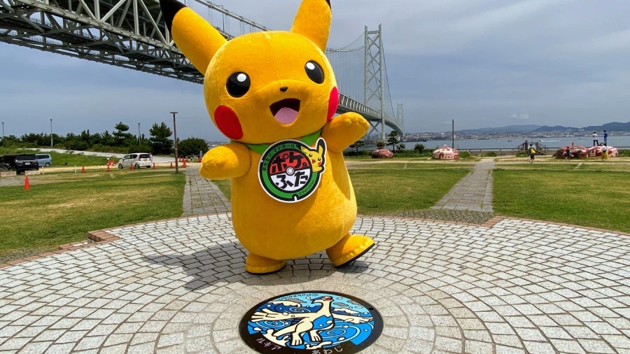 Pikachu stands in front of the Akashi Kaikyo Bridge with the newly installed Lugia manhole cover.  (Image: ©2021 Pokémon. ©1995-2021 Nintendo/Creatures Inc./GAME FREAK inc.)